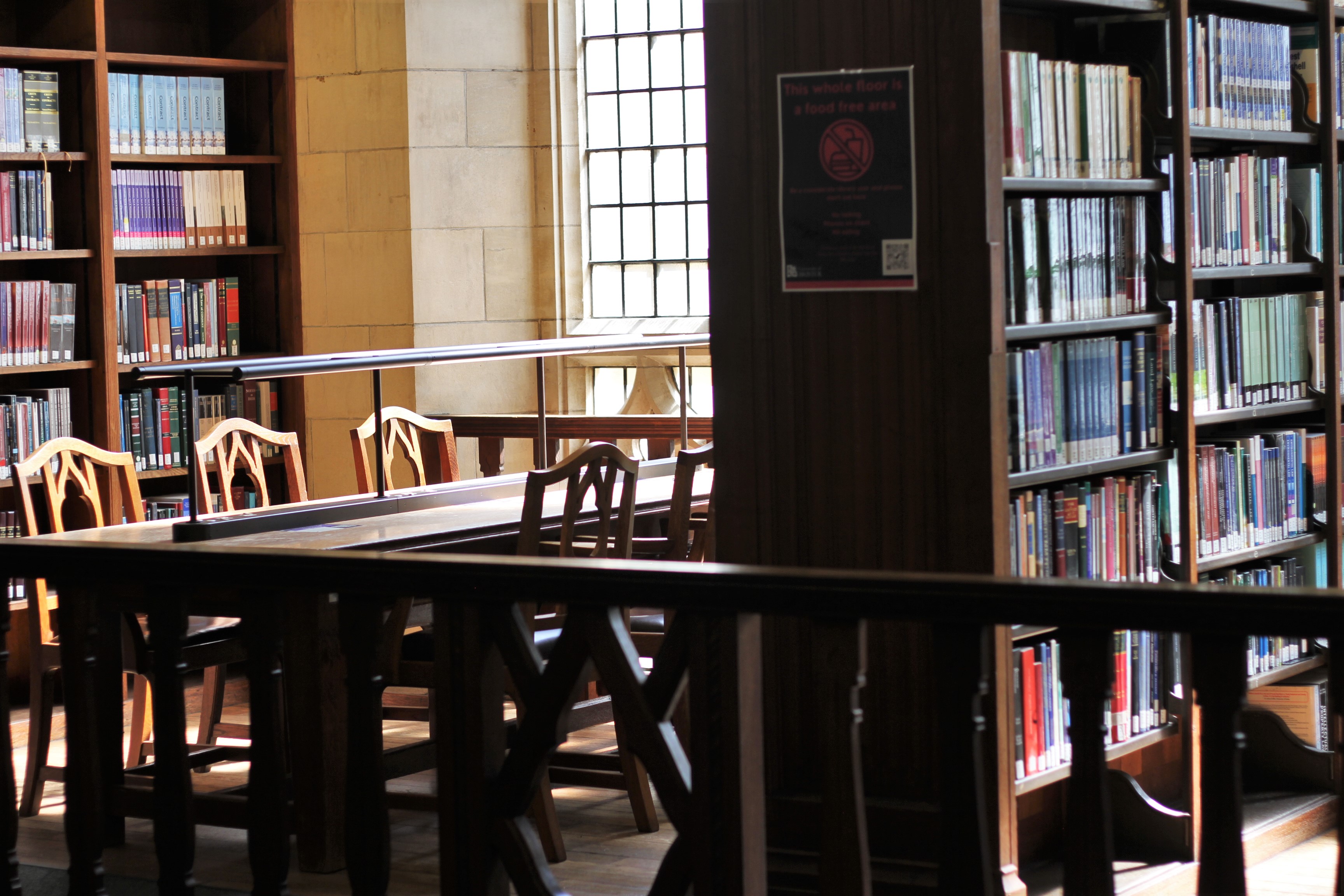 A desk with chairs sat within a nook of bookcases on the upper balcony of the wills memorial library